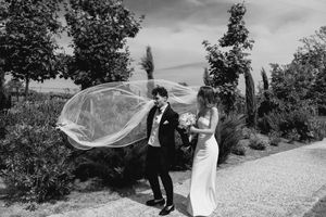 Wedding veil flows dramatically in the wind during an outdoor photoshoot.