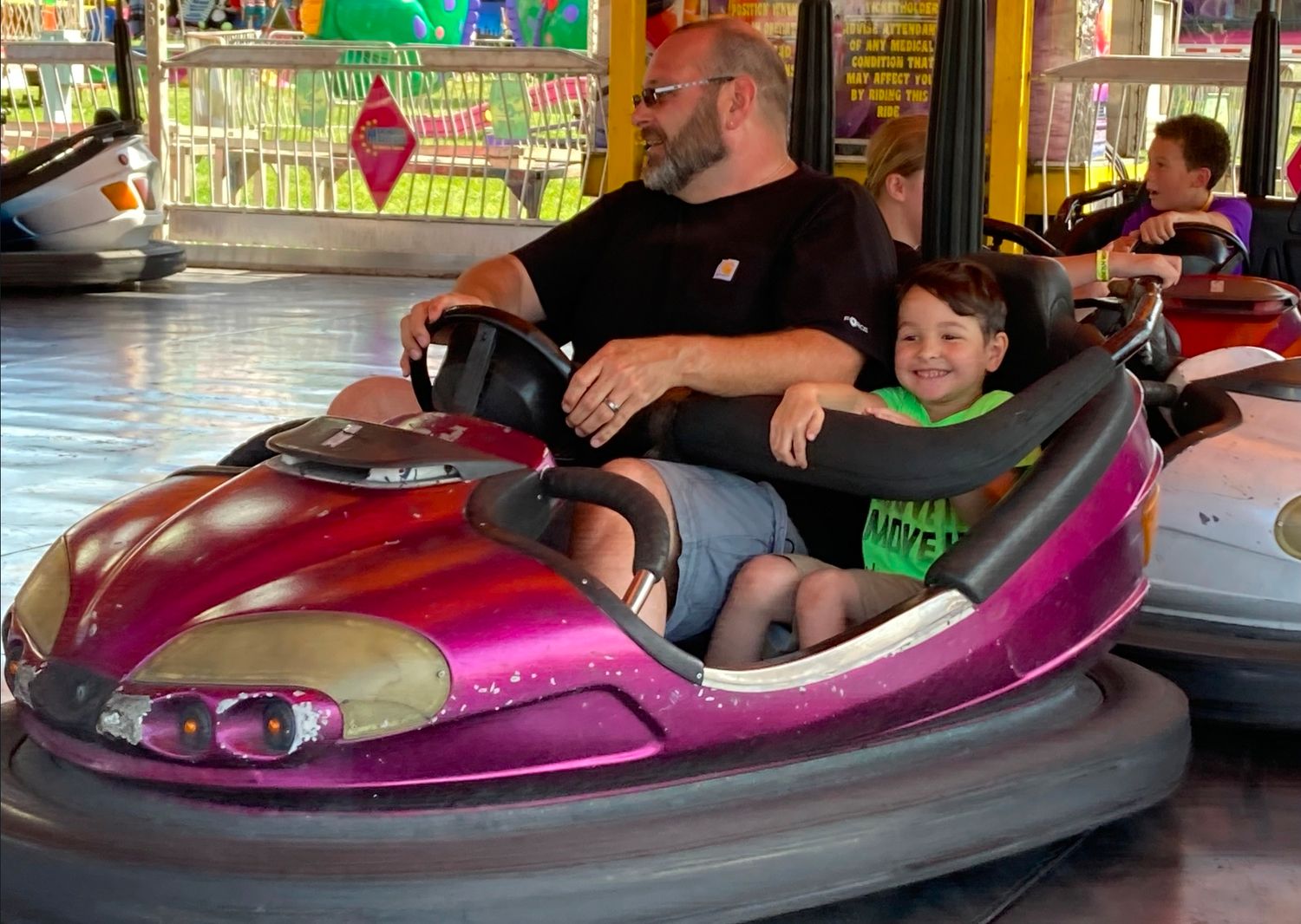 Parent and child enjoying a bumper car ride together during a family adventure.