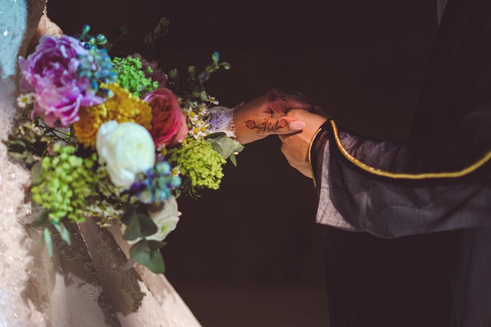 Bride and groom exchanging rings with a colorful wedding bouquet featuring purple, pink, and green flowers.