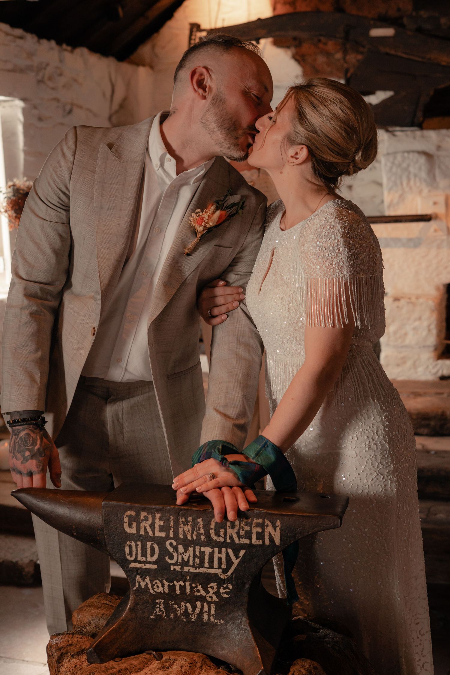 couple kiss over the anvil at Gretna Green, captured by Scottish elopement photographer
