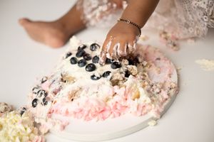 Child posing in a custom floral birthday setup during a cake smash session