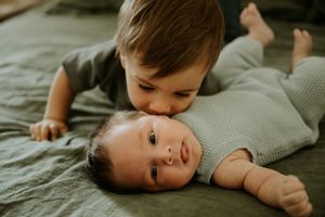 Older sibling cuddling and kissing the newborn baby during an in-home family newborn session.