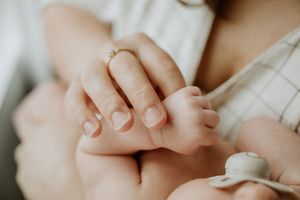 Close-up of a newborn baby’s tiny hand holding a parent’s finger during an in-home session.