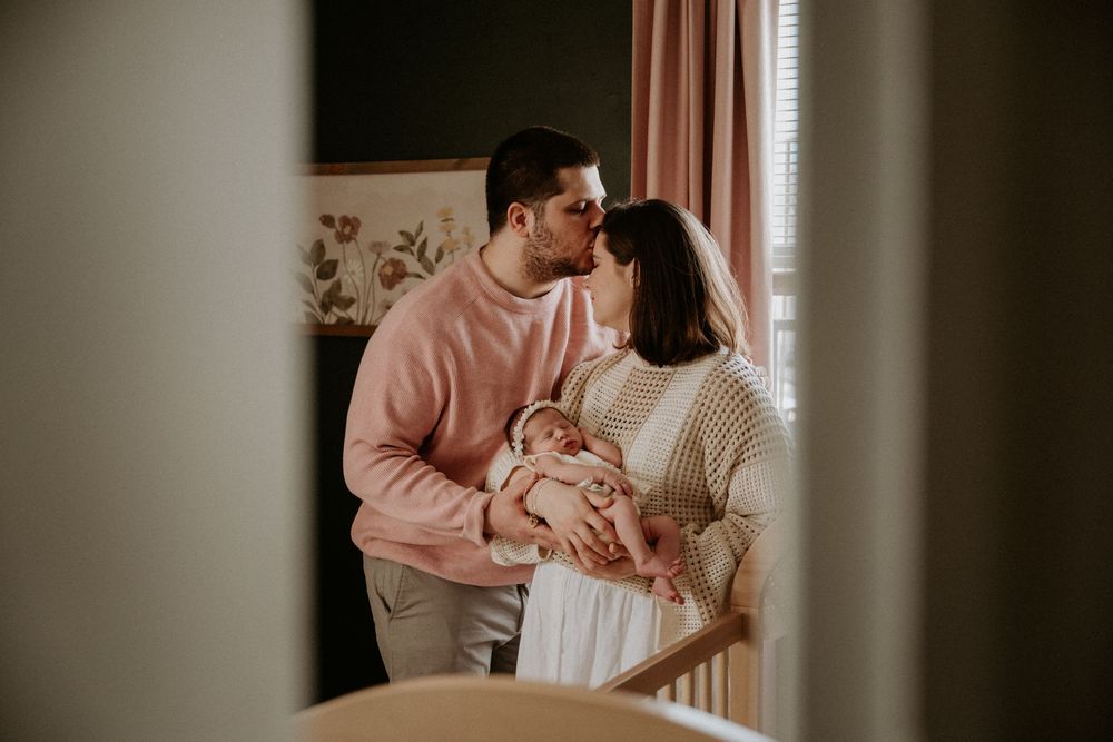 Parents holding their newborn baby together during an in-home lifestyle newborn session in New Jersey.