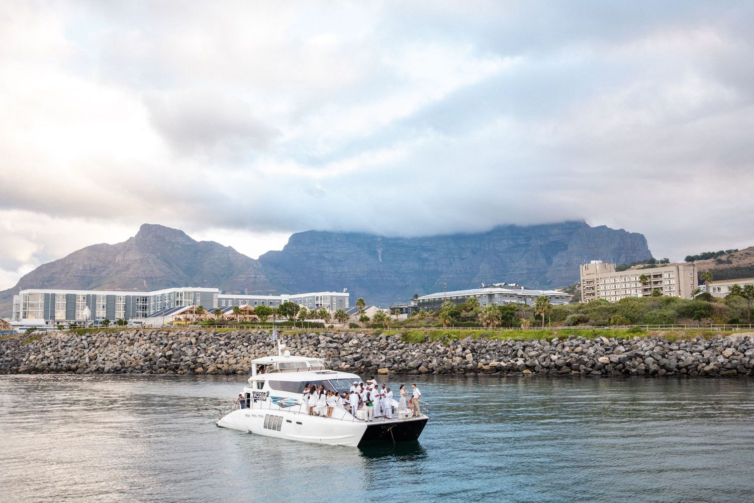 White catamaran cruising Table Bay with iconic Table Mountain backdrop in Cape Town, South Africa.
