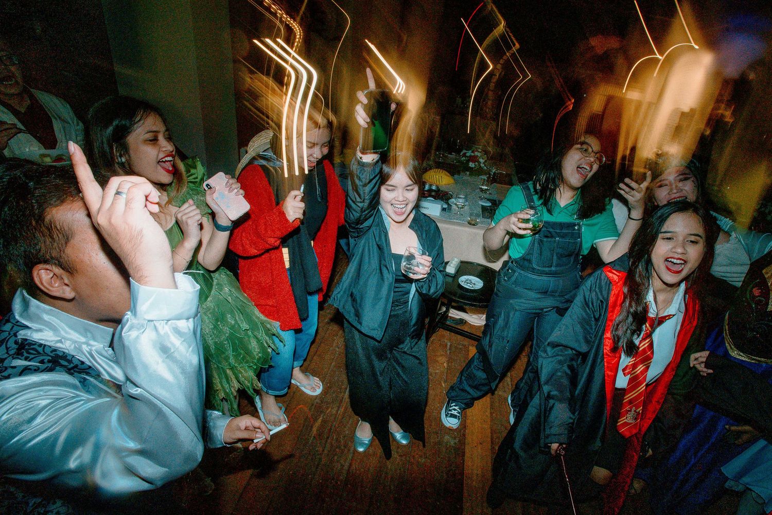 Group of young people dancing and celebrating at a lively indoor party event with festive decorations.