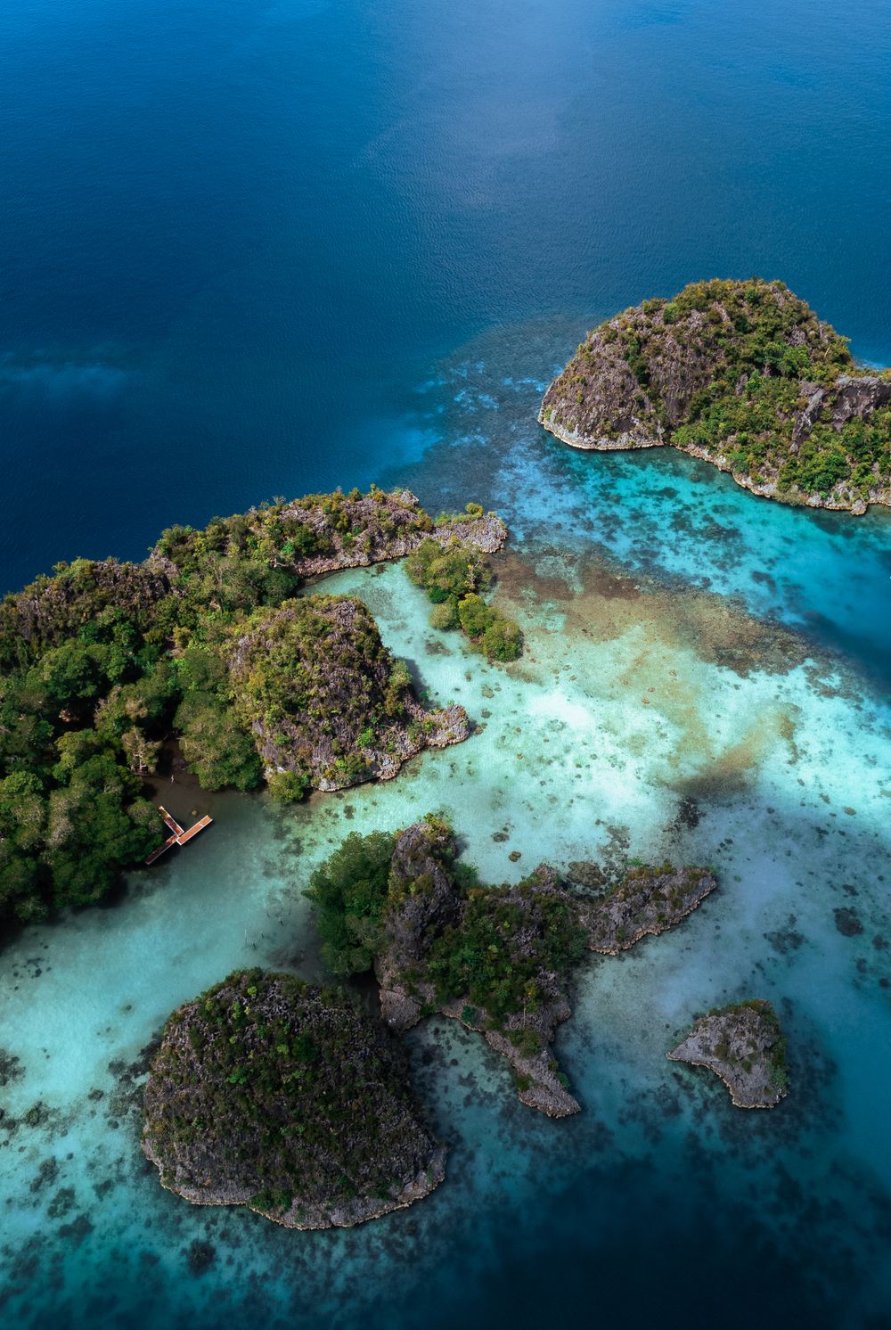 Aerial view of lush green tropical islands surrounded by vibrant turquoise and deep blue ocean waters.