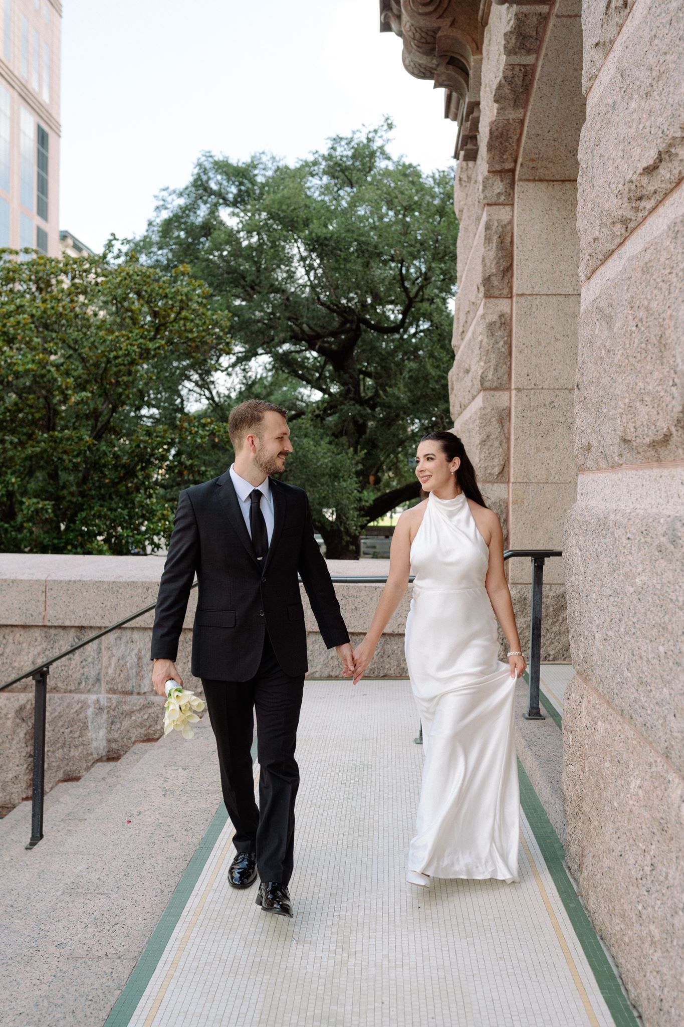 Bride and groom holding hands walking on the steps of the historic 1910 Courthouse.