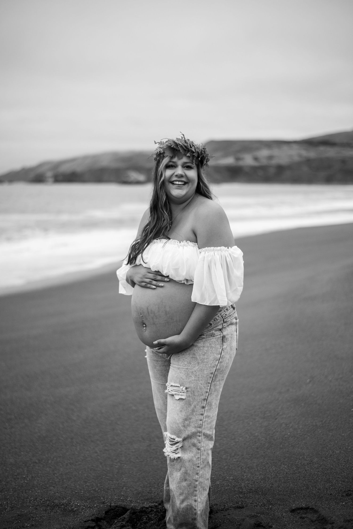 Cinematic maternity portrait of a woman at Goat Rock Beach, surrounded by rugged coastline, ocean air, and natural beauty.