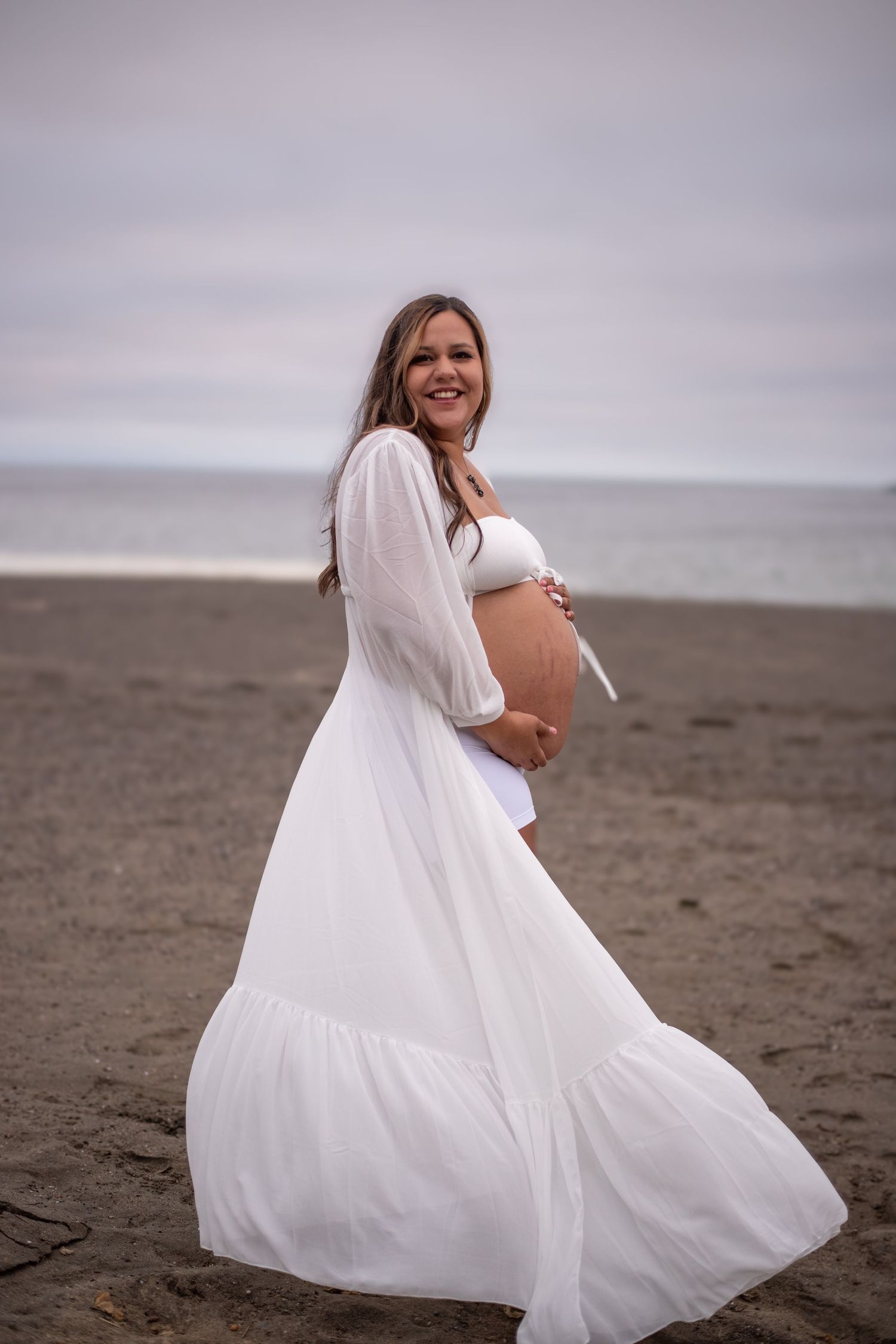 Cinematic maternity portrait of a woman at Goat Rock Beach, surrounded by rugged coastline, ocean air, and natural beauty.
