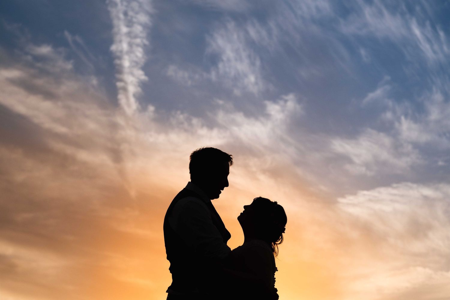 Couple silhouetted against a dramatic sunset sky on their wedding day in Surrey