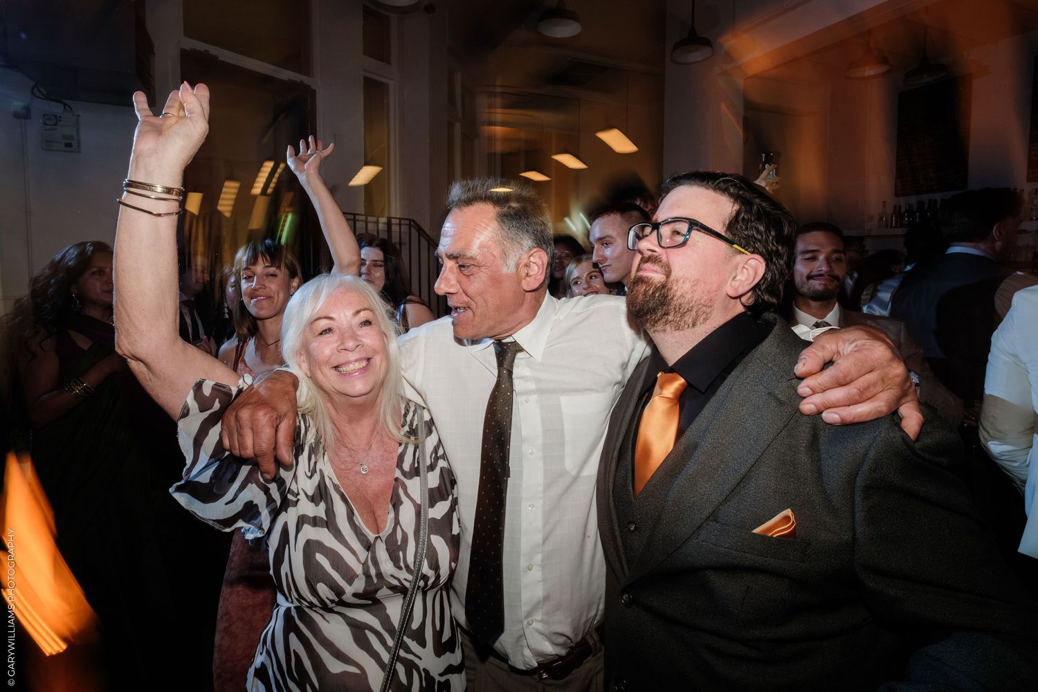 Group of people dancing and celebrating at an indoor party event, smiling and having fun together.