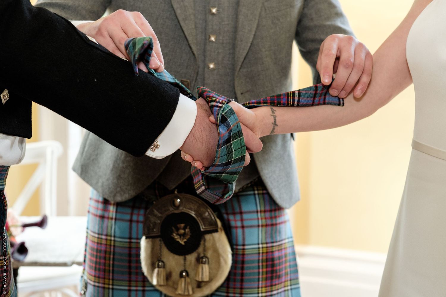Close-up of a Scottish wedding handfasting ceremony with tartan kilt and sporran.