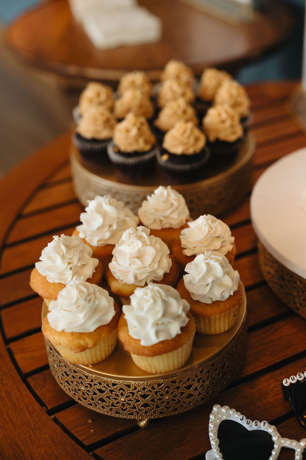 Elegant wedding dessert table with white frosted vanilla cupcakes and caramel topped chocolate cupcakes on gold stands.