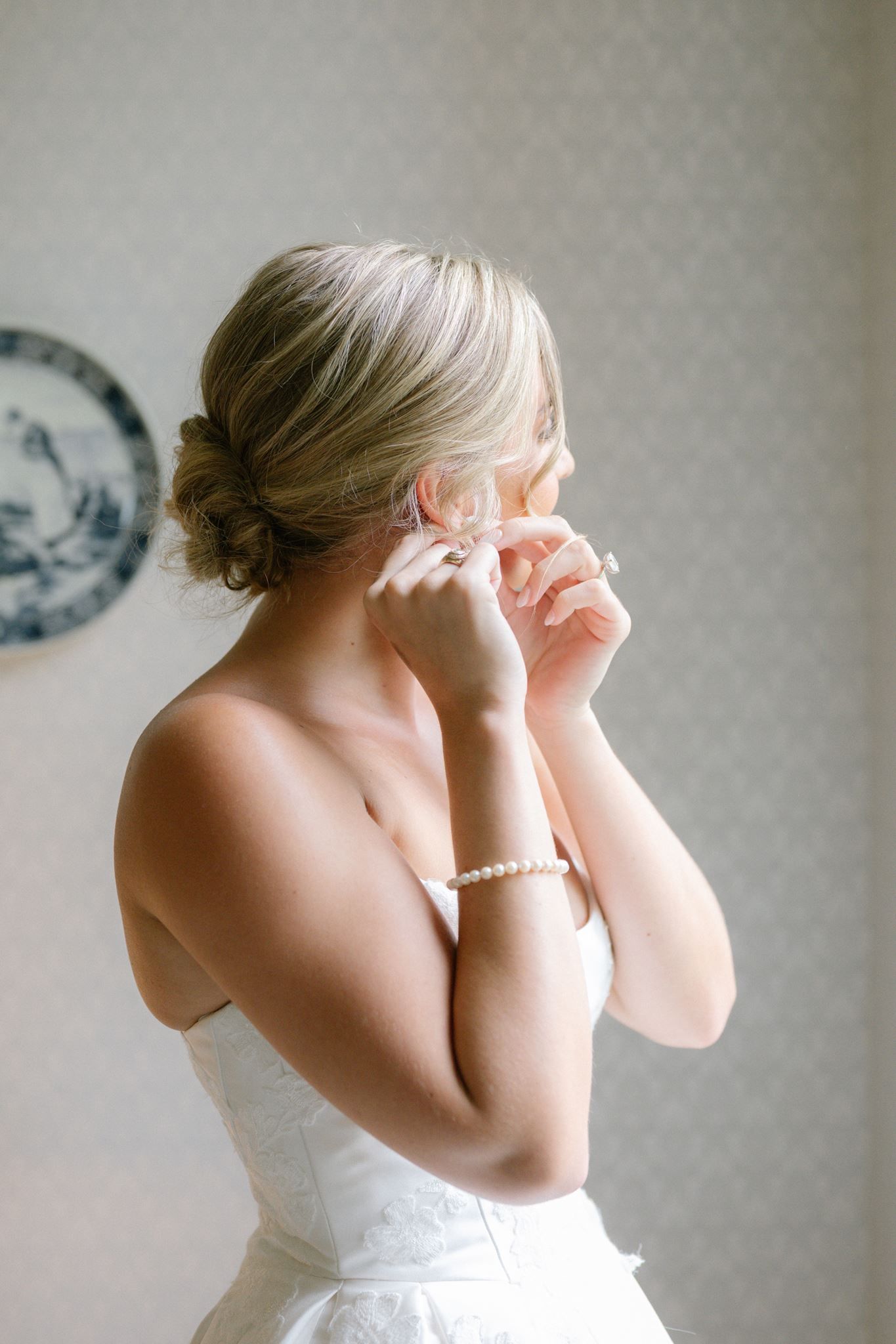 Bride putting her earrings on in front of a window at Historic Hill House in Willis Texas.