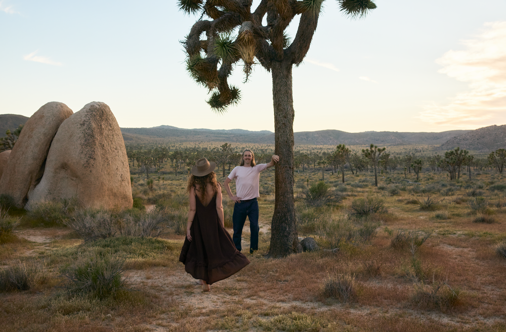 Couple holding hands near a Joshua tree at sunset in Joshua Tree National Park, California.