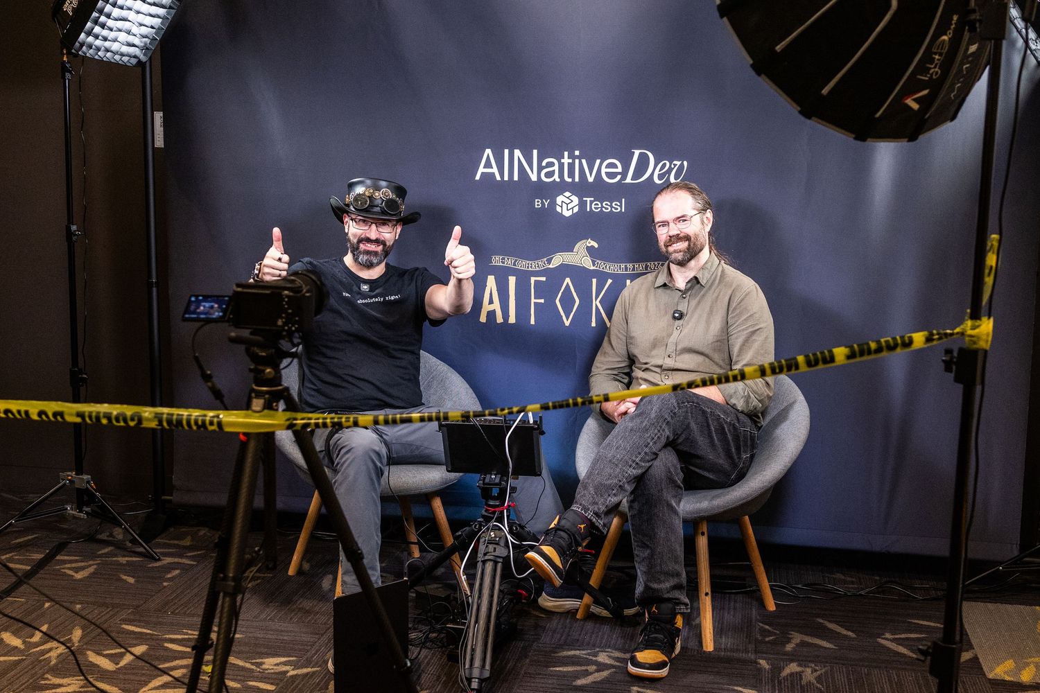 Two men giving thumbs up at AINativeDev AI Fokus interview studio setup.