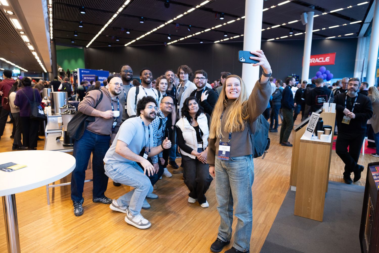 Group of tech professionals taking a selfie at an Oracle conference expo hall event.