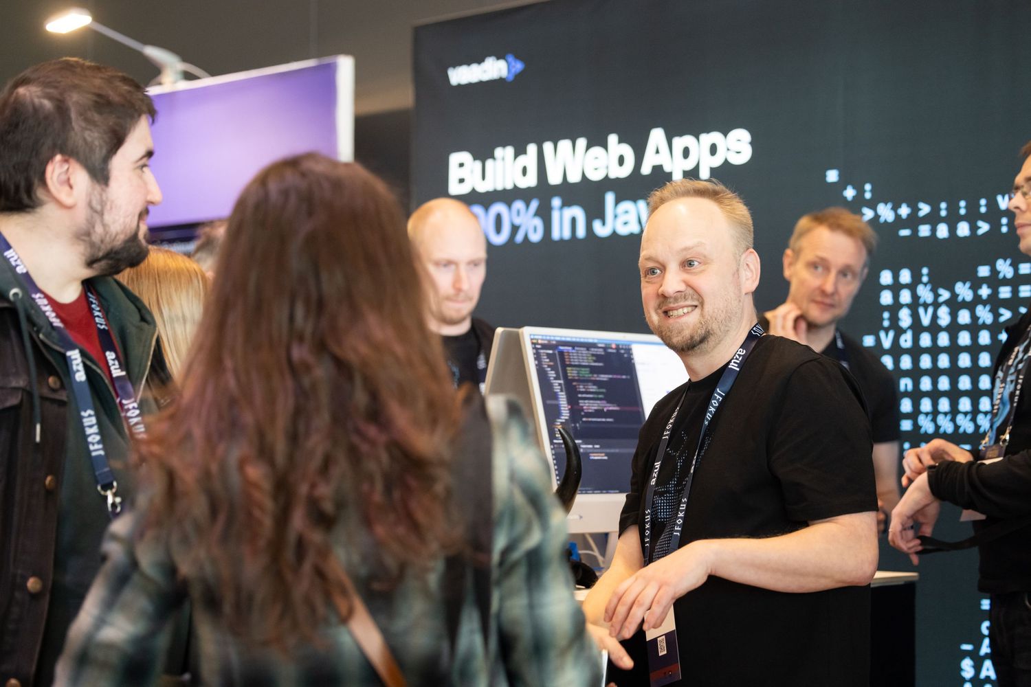 Developer engaging with attendees at a Vaadin booth promoting building web apps in Java at a tech conference.