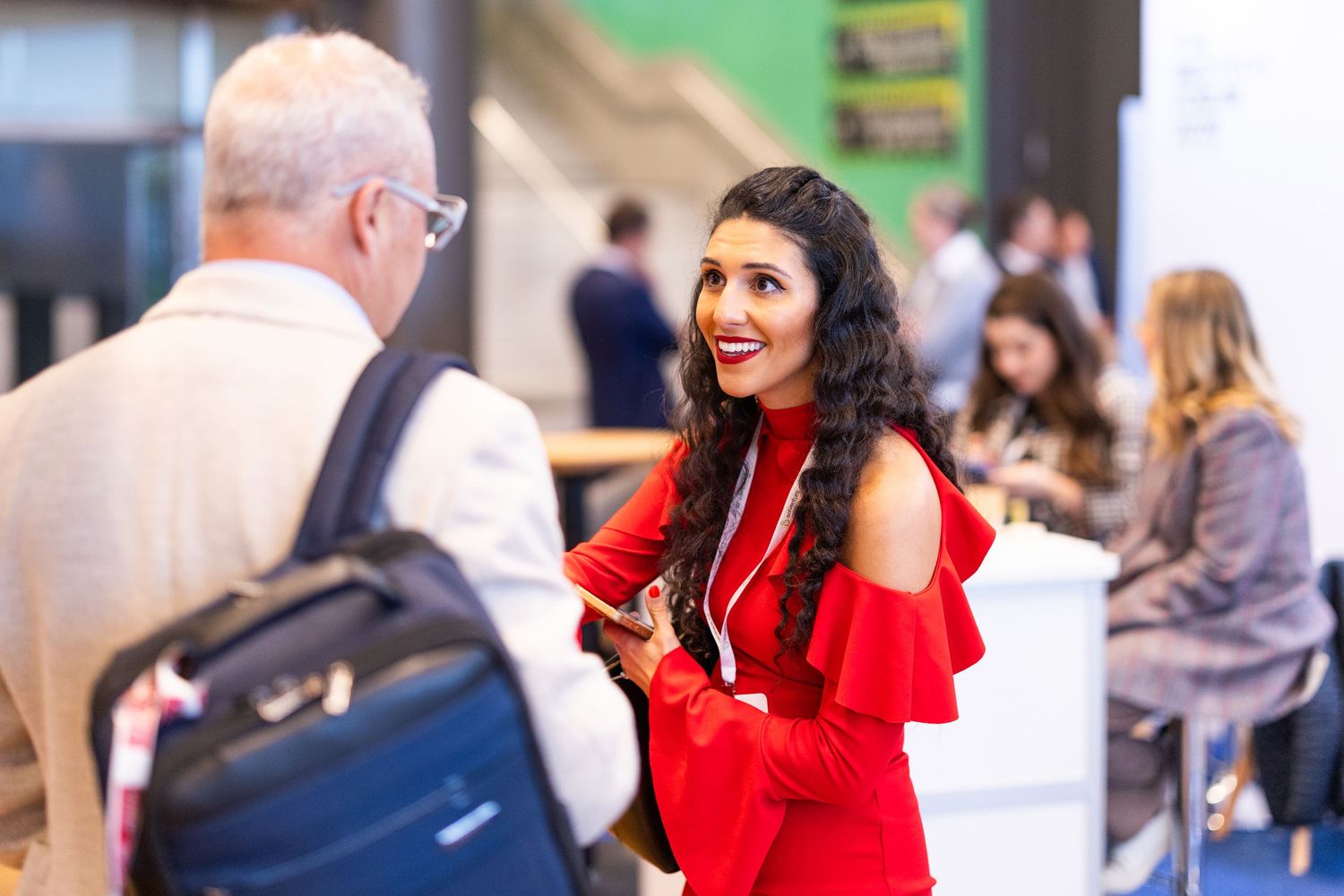 Woman in red dress engaging in conversation at a professional networking conference.