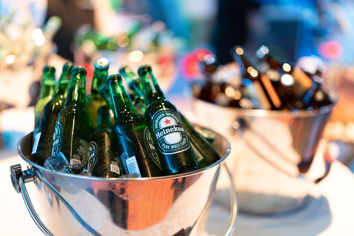 Heineken beer bottles chilling in an ice bucket at an outdoor event.