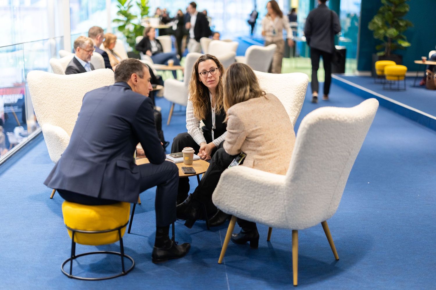 Business professionals networking in a modern lounge area at a corporate conference.