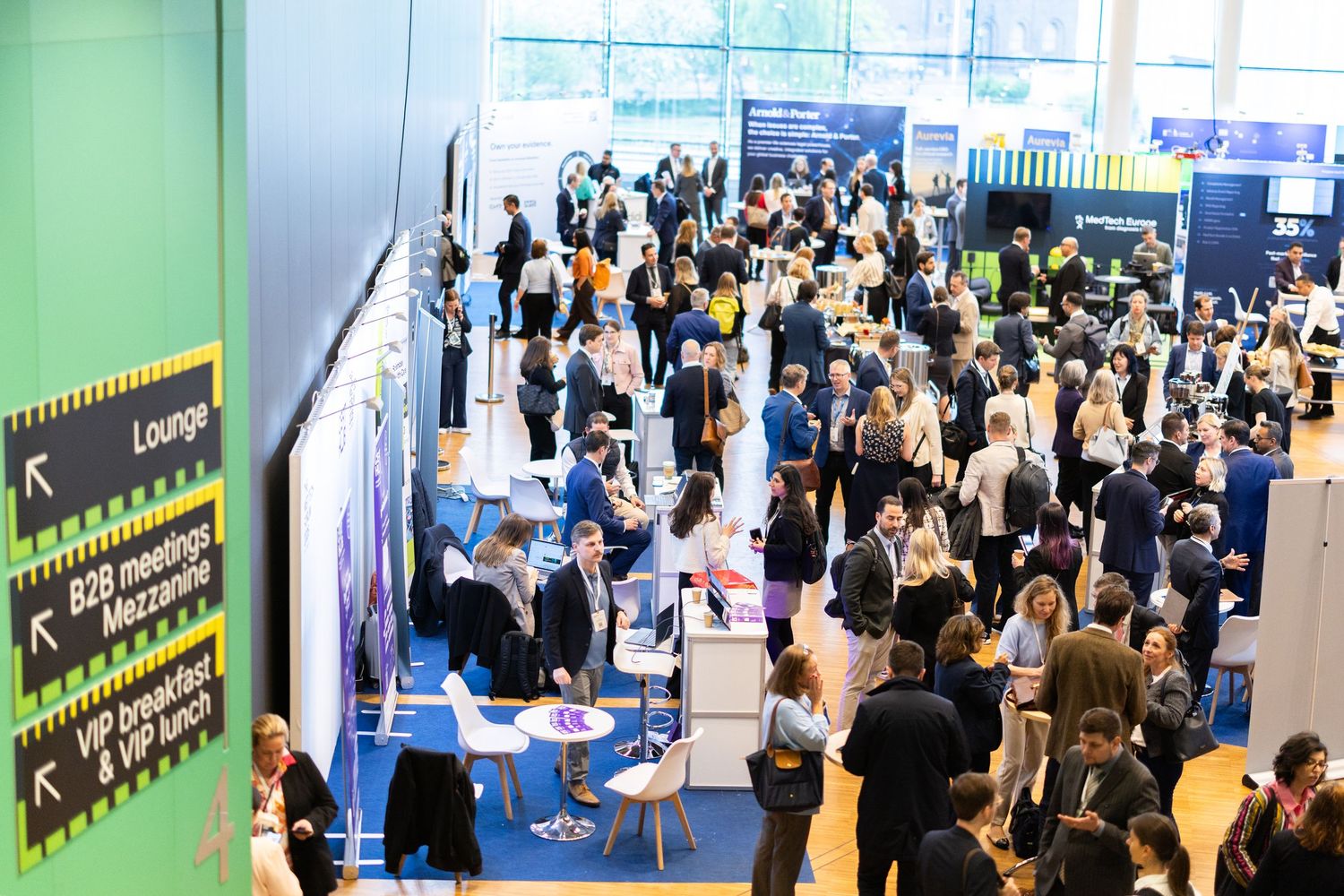 Busy exhibition hall filled with attendees networking at a large business conference.