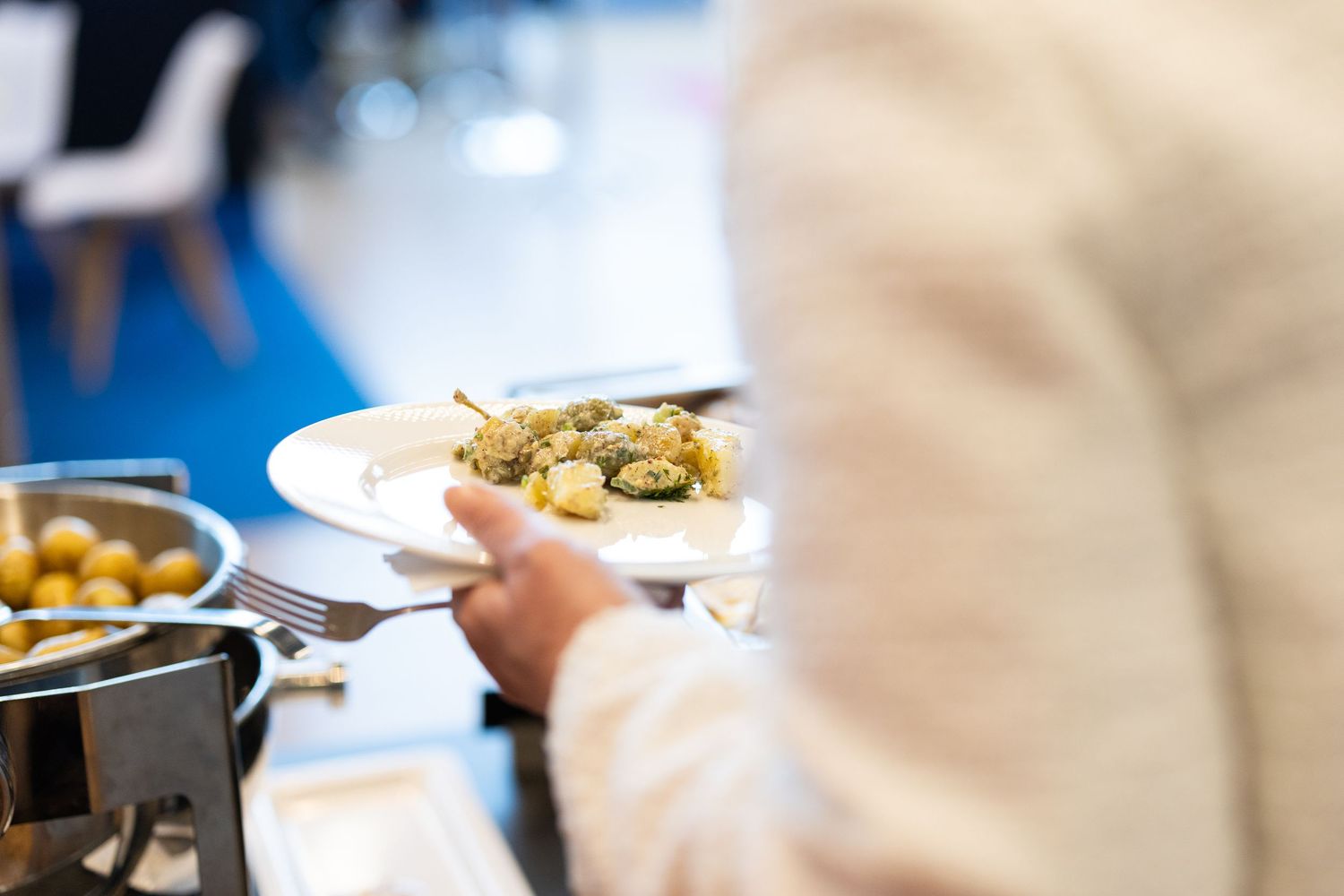 Person holding a plate of appetizers at a professional corporate catering event.