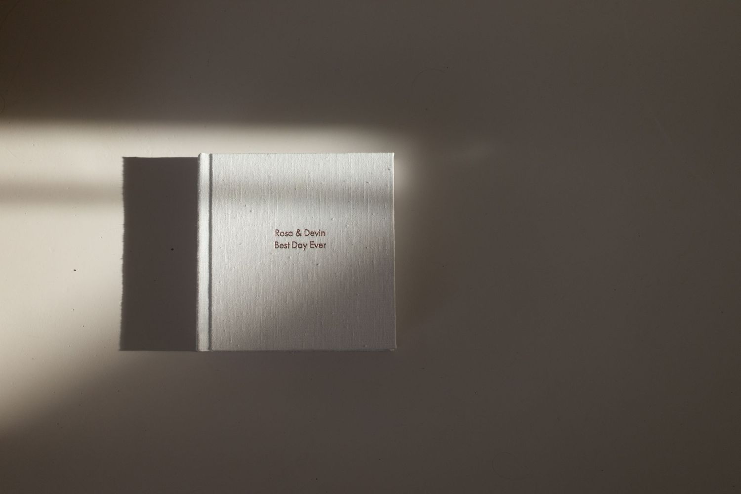 Minimalist photo album book with text on cover in dramatic lighting.