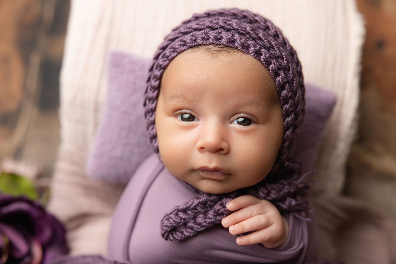 Newborn baby in teal hooded knit onesie with wooden buttons, sitting in a vintage metal bucket with soft teal blankets.