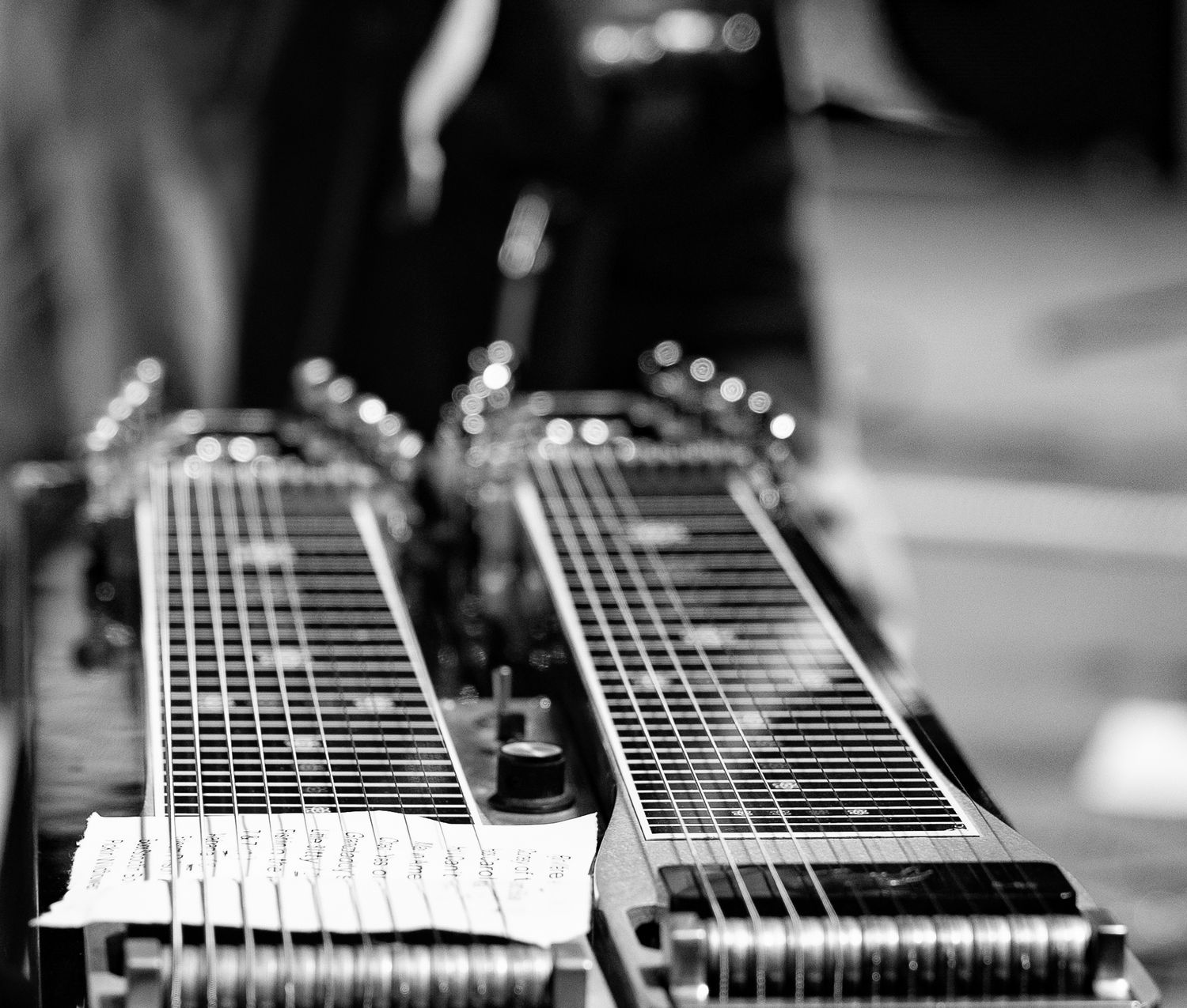 Close-up black and white photo of two lap steel guitars with strings and frets in sharp detail.