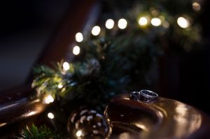 Silver ring on golden plate with pine cones, evergreen branches, and warm bokeh lights in festive holiday setting in Boyne Hill