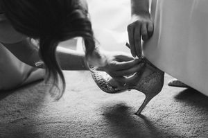 Black and white photo of a woman helping a bride put on a sparkly high heel shoe before the wedding at Boyne Hill House Estate, Co. Meath