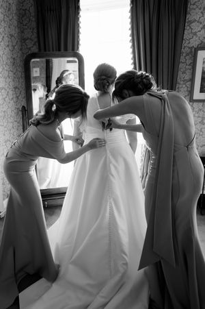 Bridesmaids helping bride with wedding dress in elegant black and white photo at Boyne Hill House Estate, Co.Meath