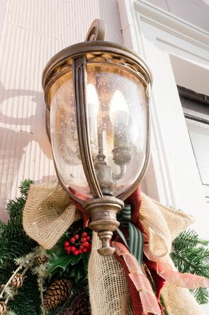 Boyne Hill House vintage brass outdoor lantern decorated with burlap bow, holly berries, and evergreen branches for Christmas.
