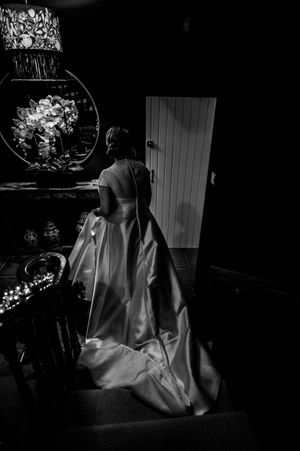 Black and white photo of a bride in a flowing gown standing before a mirror at Boyne Hill House Estate, Co.Meath