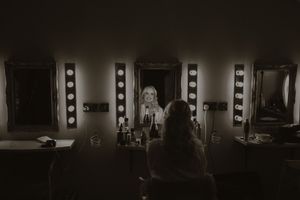 Bride sits at a vanity mirror with Hollywood lights in a dark dressing room, captured in black and white at Boyne Hill House Estate, Co. Mea
