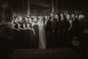 Black and white wedding party photo with bride, groom, bridesmaids in dark gowns, and groomsmen in suits posing indoors at Boyne Hill House