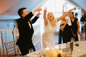 Joyful bride and groom celebrating at wedding reception, raising hands and laughing with guests Boyne Hill House Estate