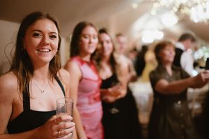 Wedding guests in elegant dresses smiling and holding champagne glasses in a warmly Boyne Hill House Estate