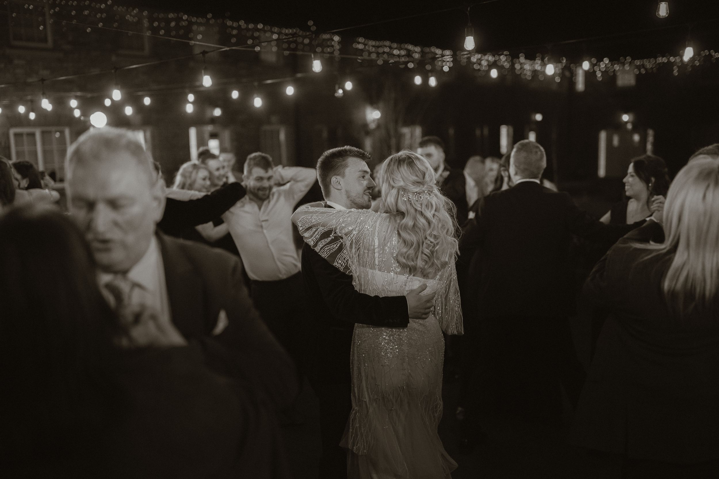 Couple shares romantic first dance under string lights at elegant evening wedding reception at Boyne Hill House Estate, Co. Meath