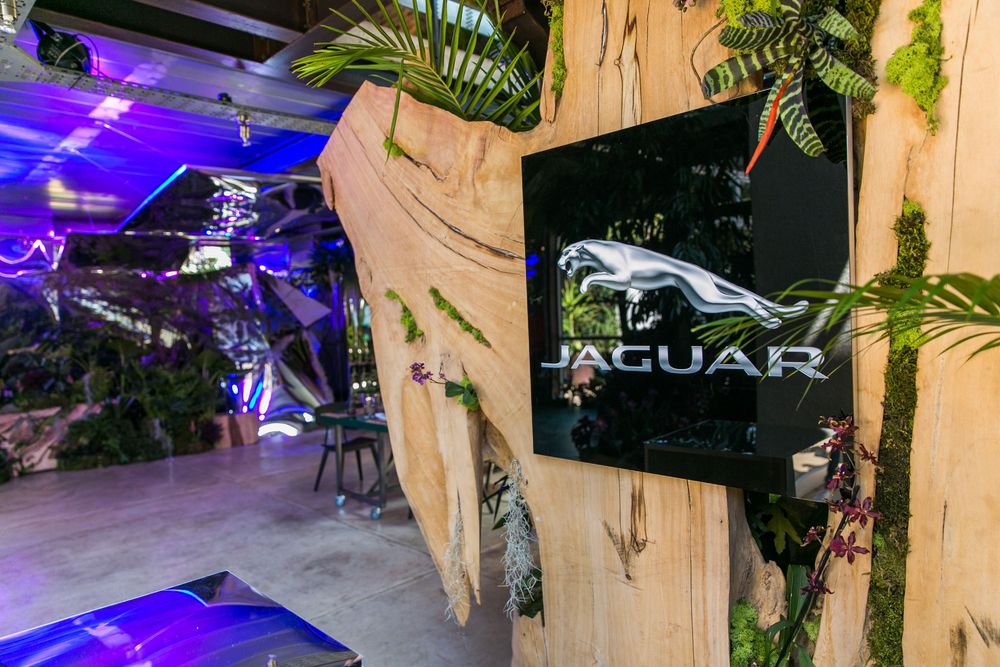 Jaguar branded display with leaping cat logo surrounded by tropical plants and purple lighting at an upscale event.