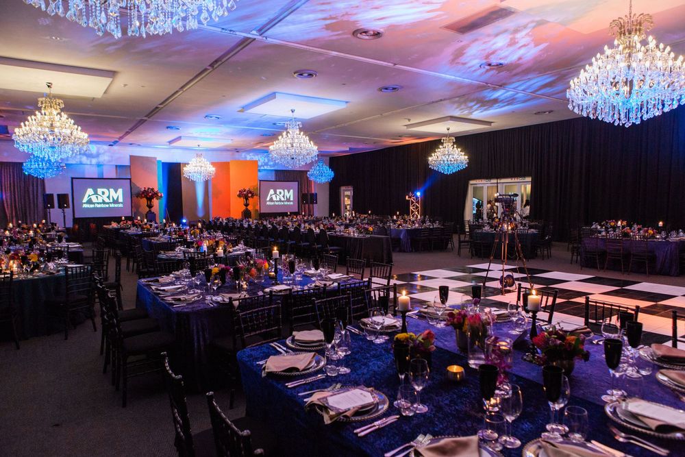 Elegant ARM event ballroom with blue tablecloths, crystal chandeliers, and checkered dance floor.
