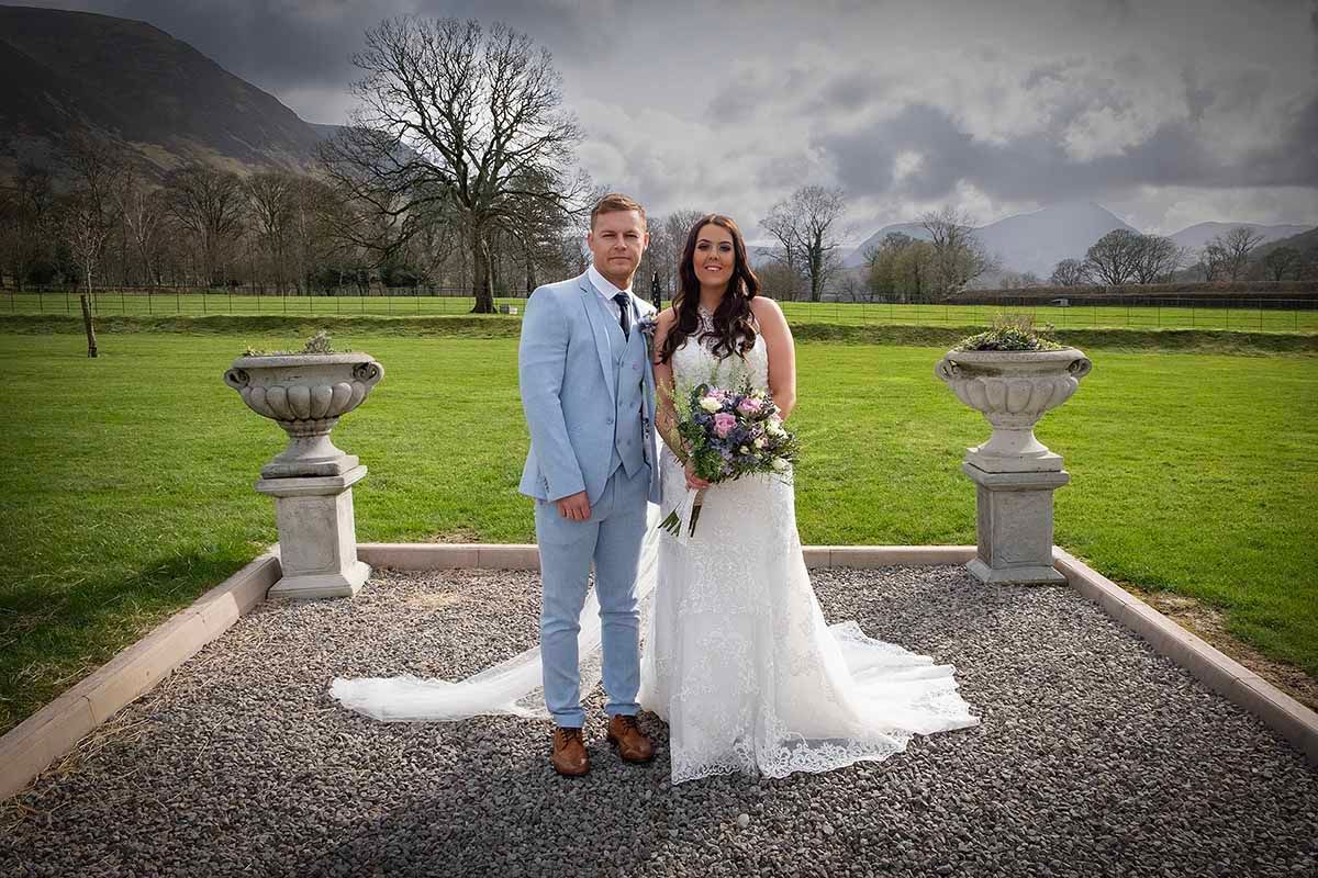 Bride and groom posing on gravel path outside New House Farm wedding venue Cockermouth Cumbria