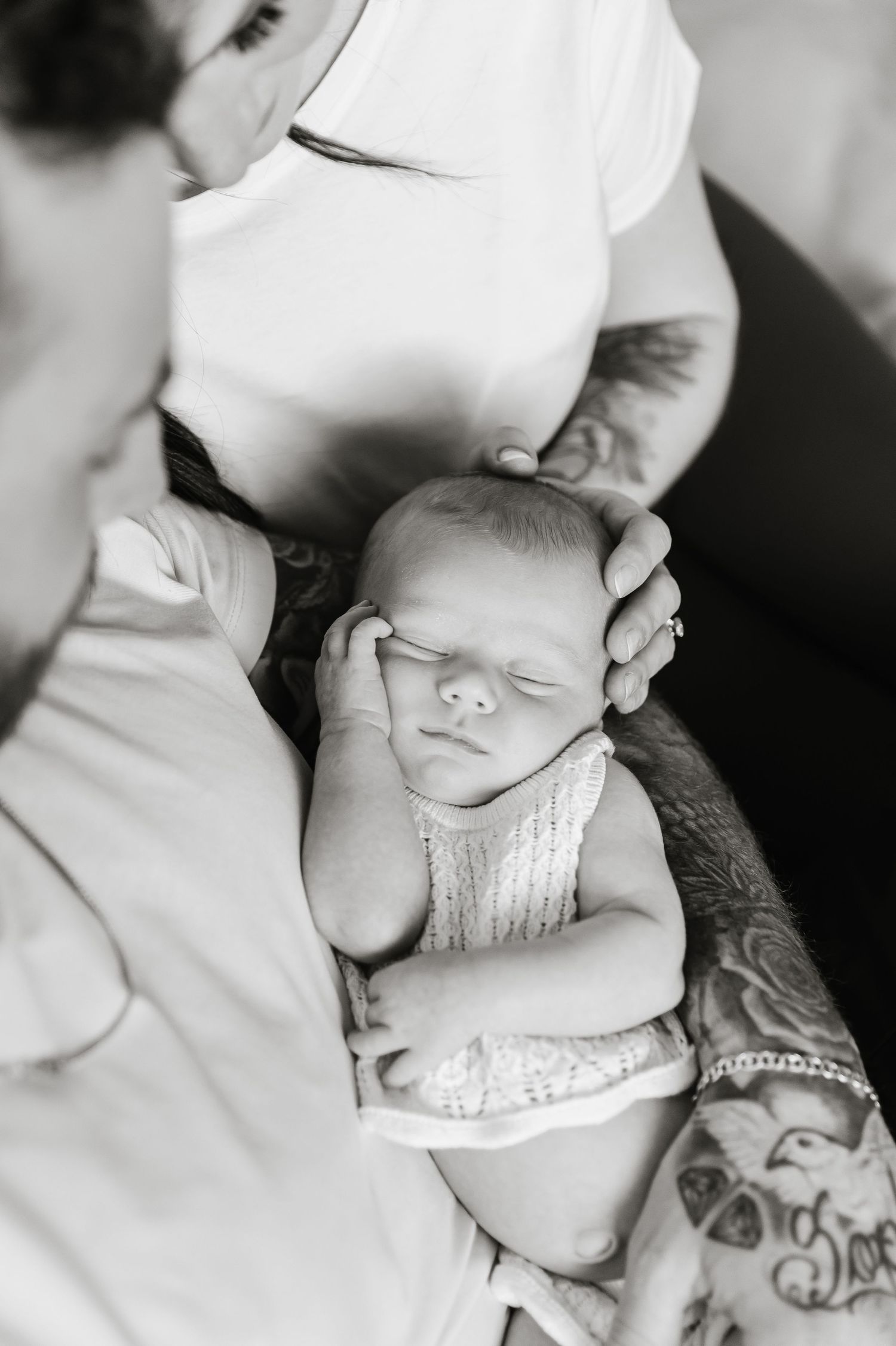 Black and white maternity photo of pregnant woman and partner tenderly cradling baby bump together.