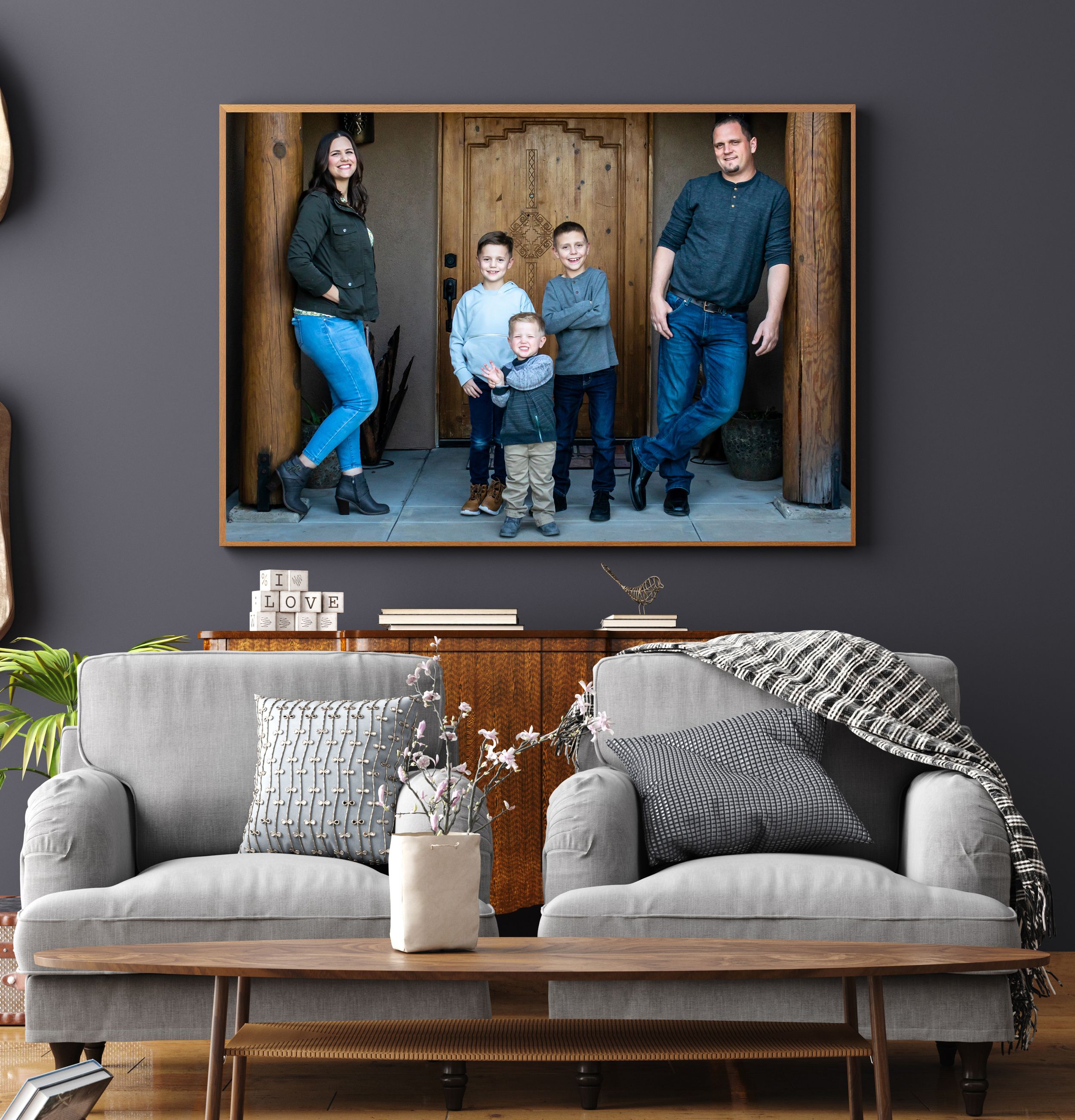 Family portrait in wooden frame displayed above gray sofa in modern living room with mid-century console table.