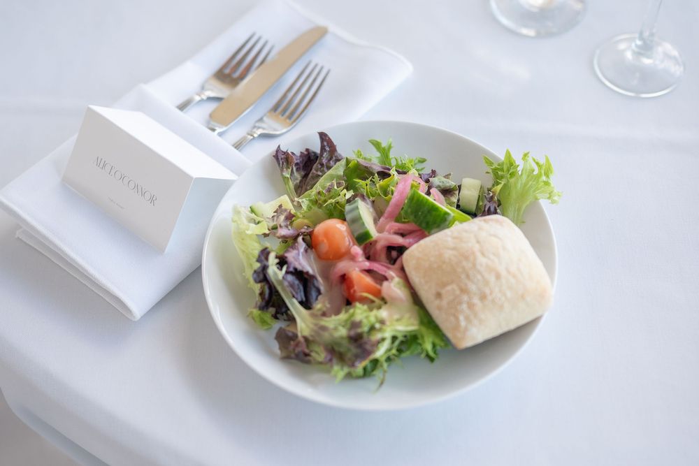 Fresh garden salad with bread roll on white plate at an elegant wedding reception.