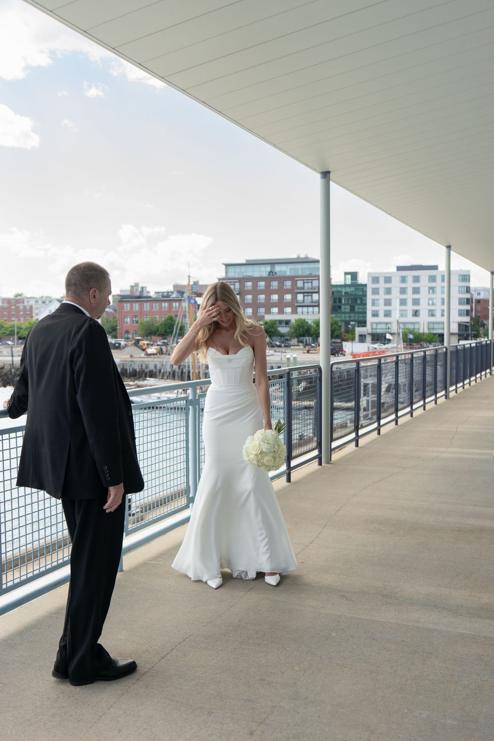 Bride in a white gown covers her face emotionally during a first look moment with groom.