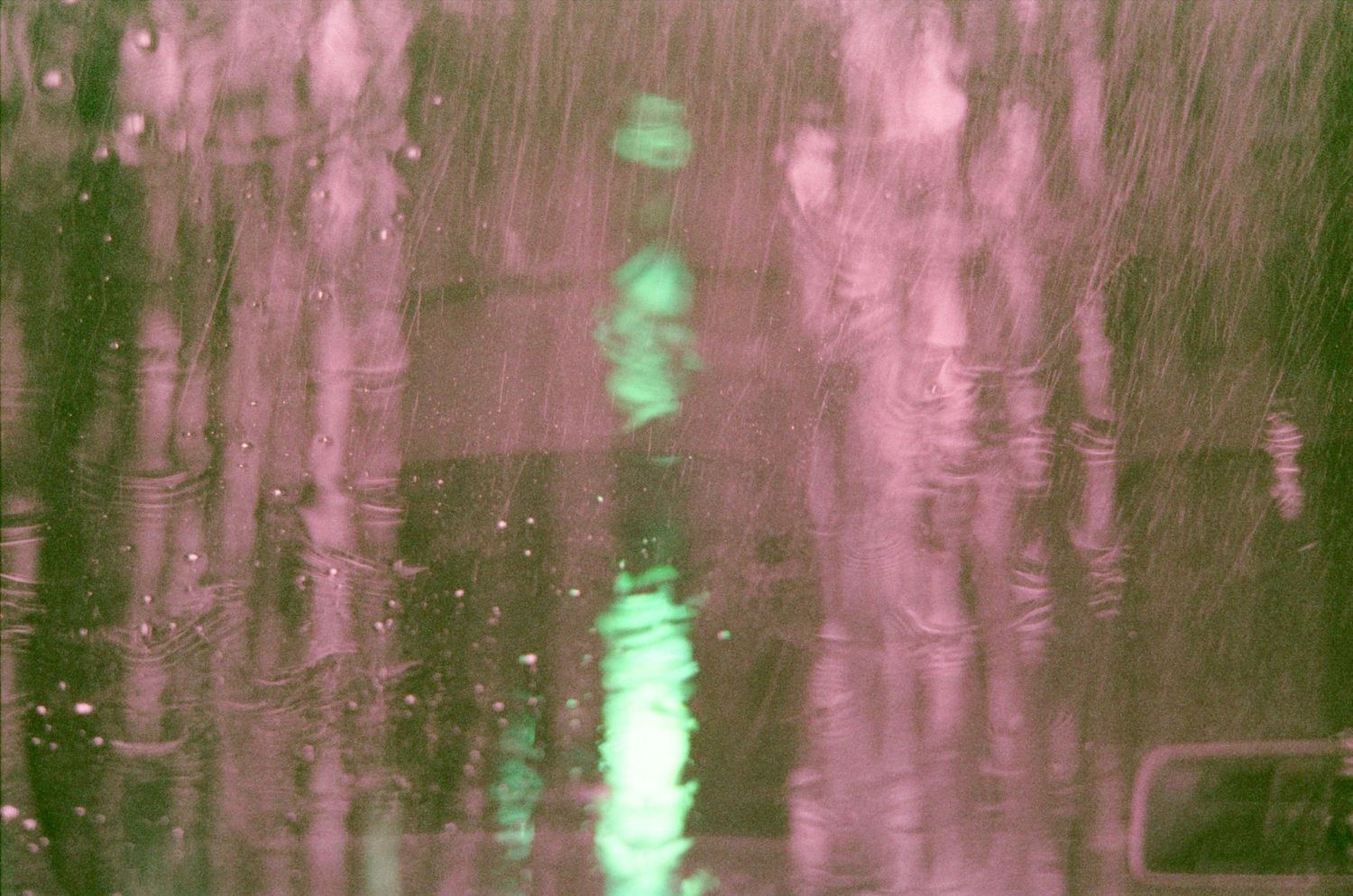 Rear view mirror of a car reflects bright lights from a vehicle behind at night on a dark road.