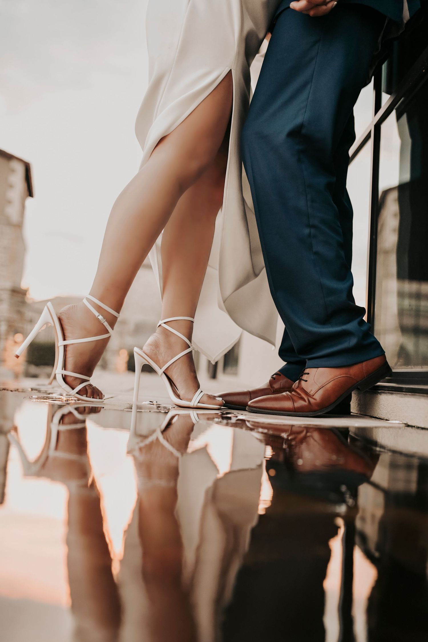 Close-up engagement photo highlighting the couple’s shoes reflected in the water
